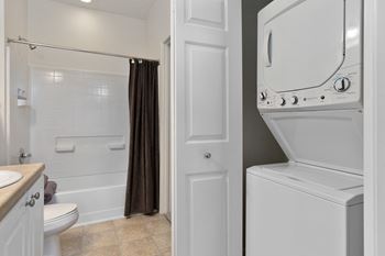 A white washer and dryer in a bathroom with a shower and a toilet